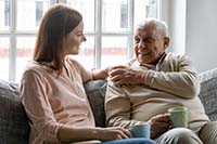 Photo of a young woman sitting with an older man, smiling